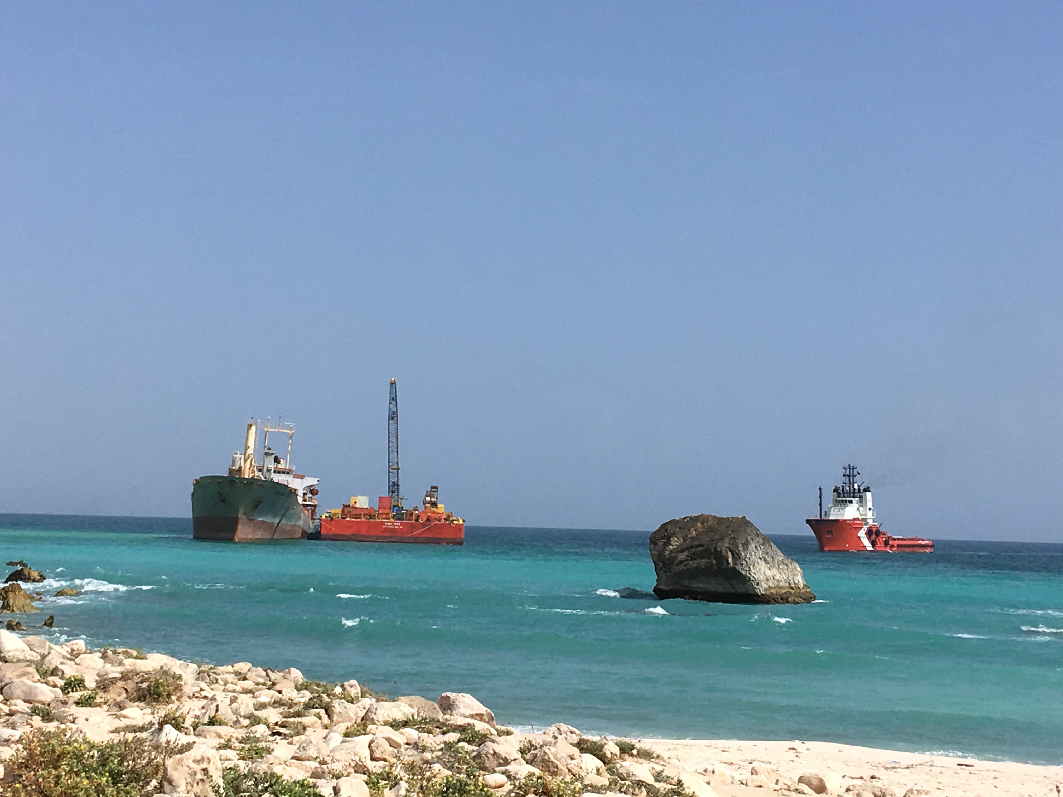 Two barges head to a dry dock on either side. There is a large rock in the foreground.